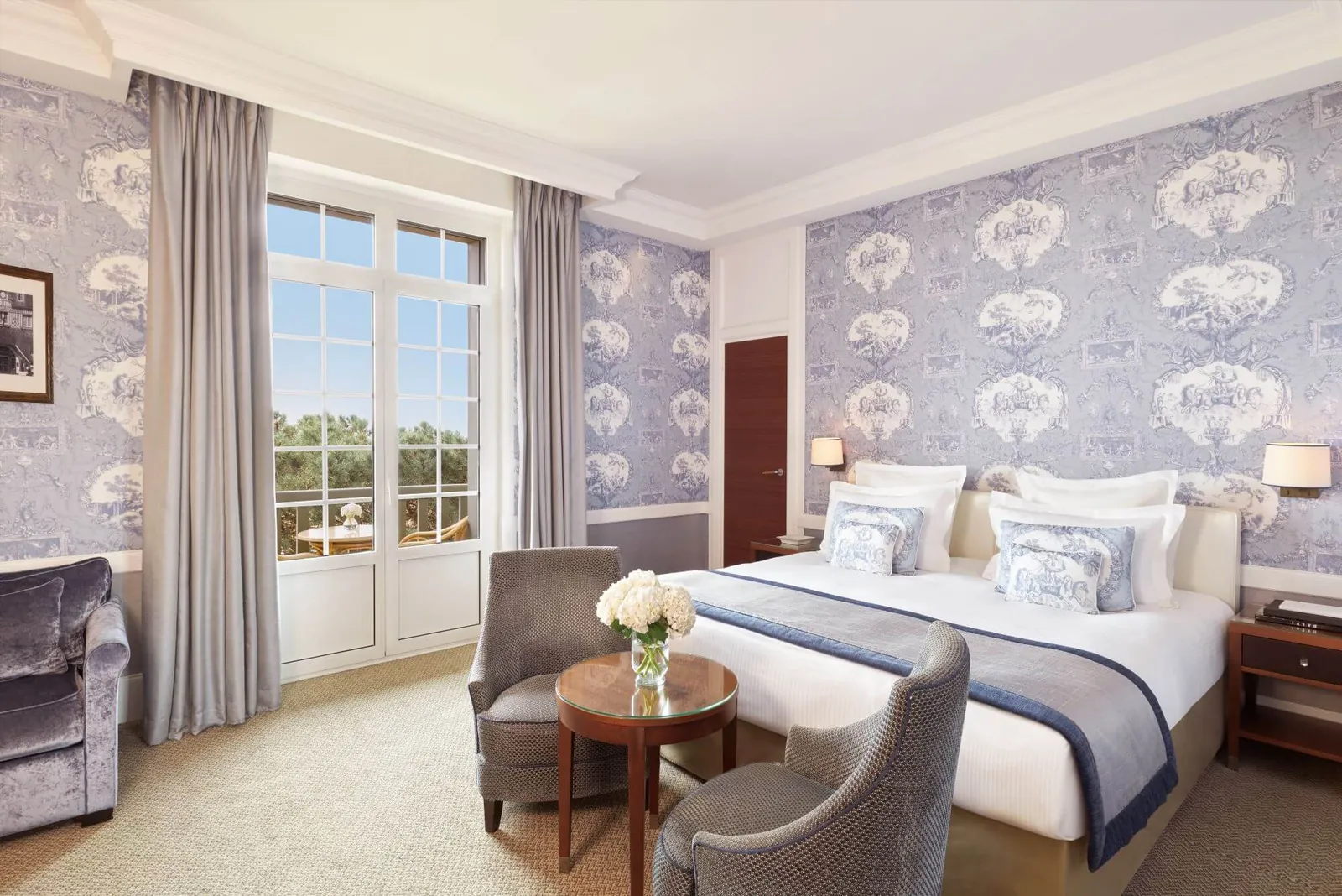 Deluxe bedroom with blue toile de Jouy wallpaper and tall windows at Hôtel Barrière Le Normandy, Deauville
