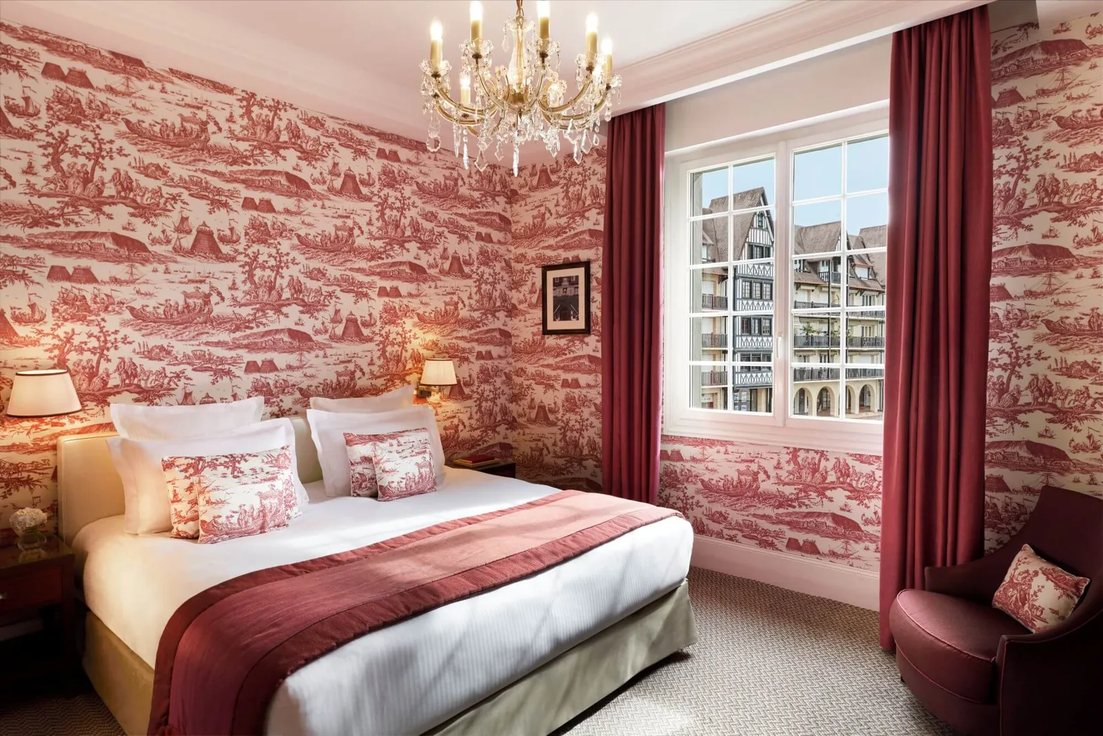 Superior bedroom with red toile de Jouy wallpaper, a chandelier and tall windows at Hôtel Barrière Le Normandy, Deauville