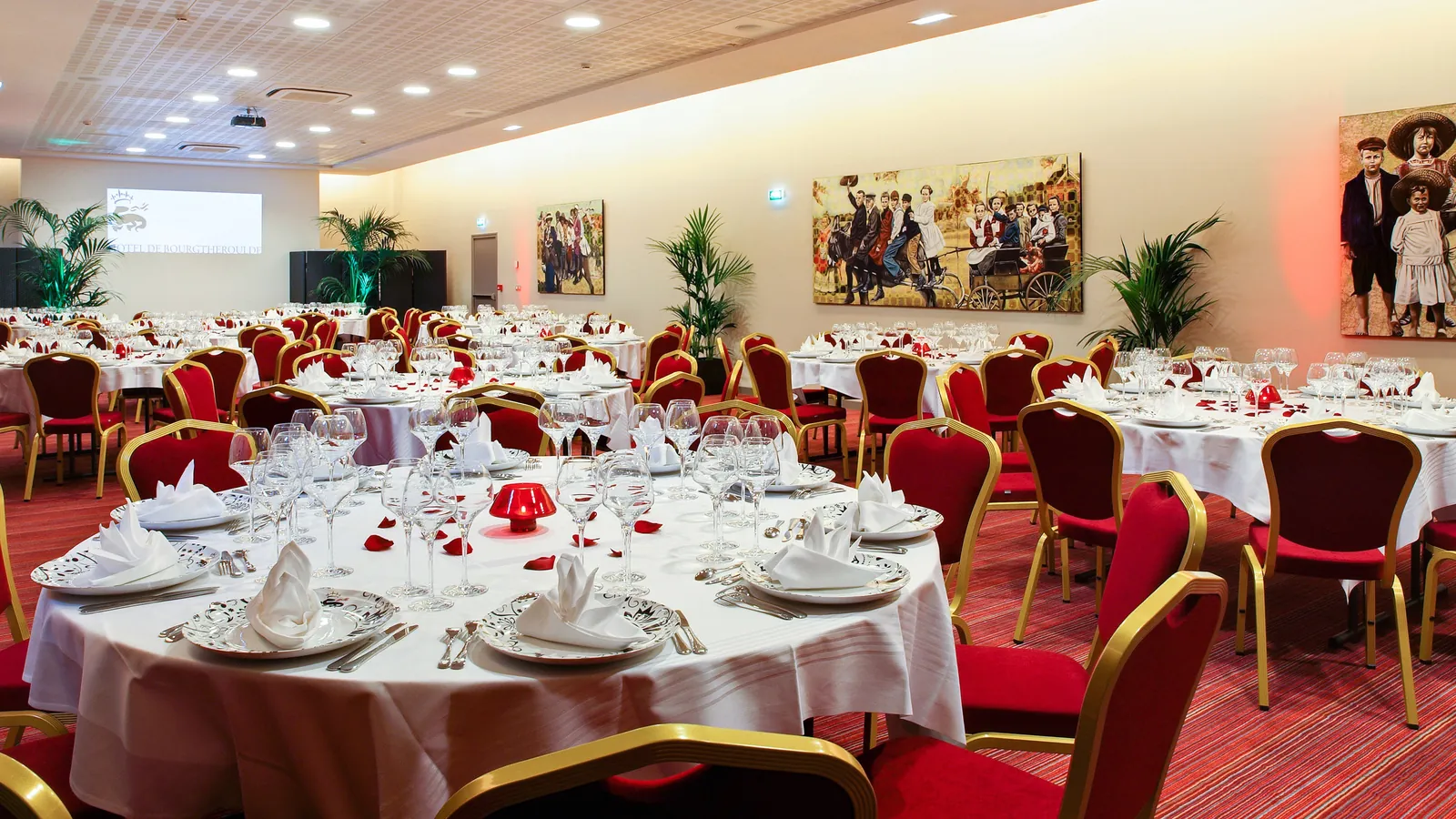 Banquet hall with round tables, red chairs and wall paintings at Hôtel de Bourgtheroulde, Rouen