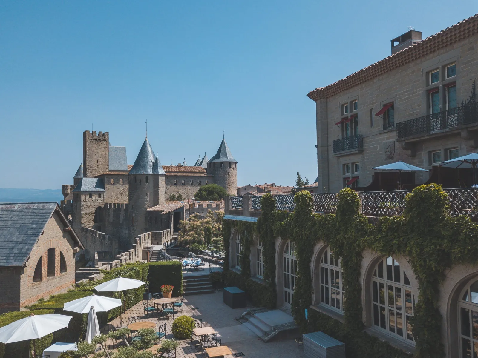 Terrasse avec parasols face aux remparts médiévaux de l'Hôtel de la Cité, Carcassonne