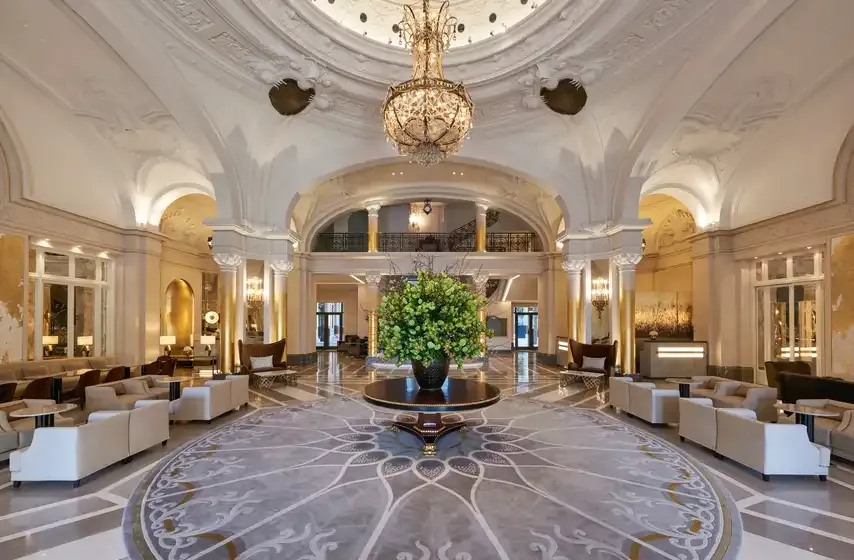 Marble lobby with a gilded chandelier, lounge seating and a central planter at Hôtel de Paris Monte-Carlo