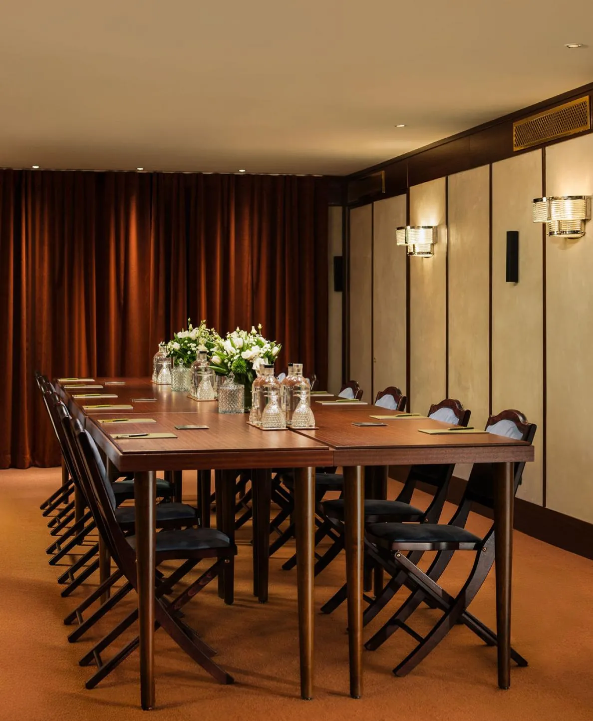 Meeting room at Hôtel des Grands Voyageurs set with a long wooden table, folding chairs and floral centrepiece