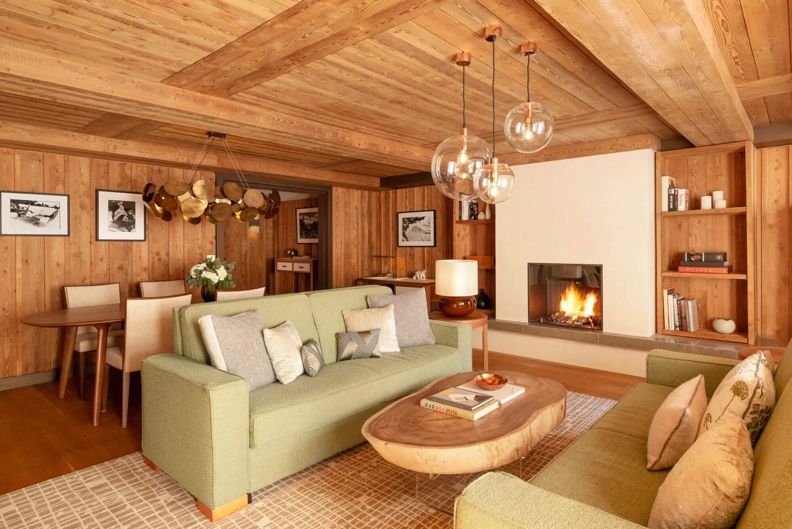 Lounge of a suite with fireplace, wooden ceiling and green sofa at Hôtel Fouquet's Courchevel