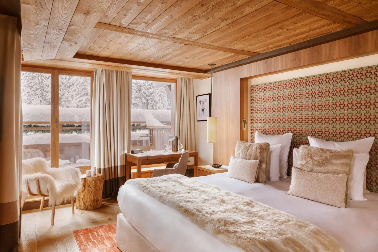 Junior suite with king bed, fur throw and snowy view through panoramic windows at Hôtel Fouquet's Courchevel