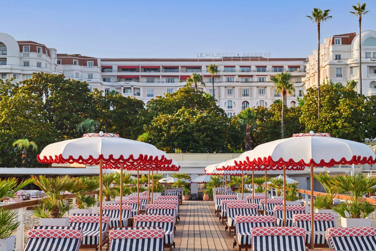 Terrace with red-and-white parasols and striped chairs in front of Hôtel Majestic Barrière, Cannes
