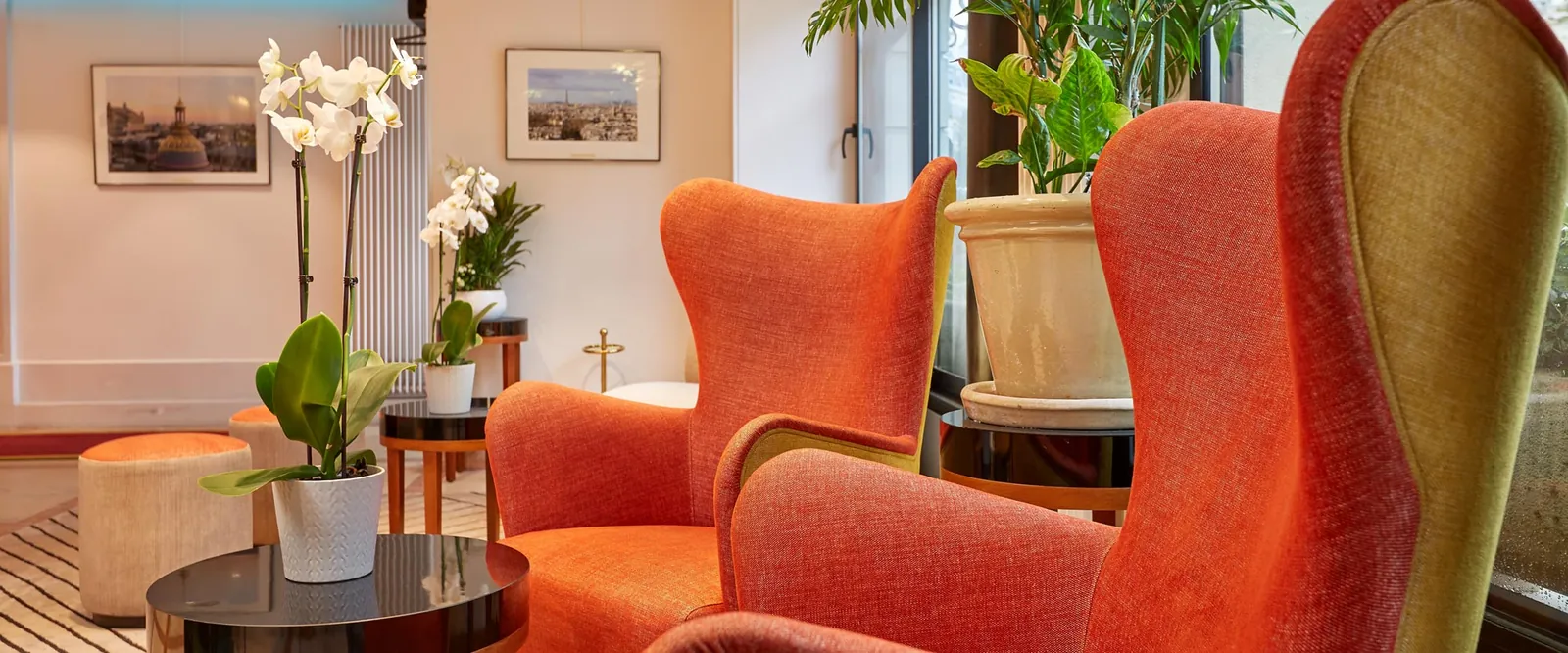Reception and lounge of Hôtel Minerve Paris with orange armchairs and orchids in the Latin Quarter, 5th arrondissement