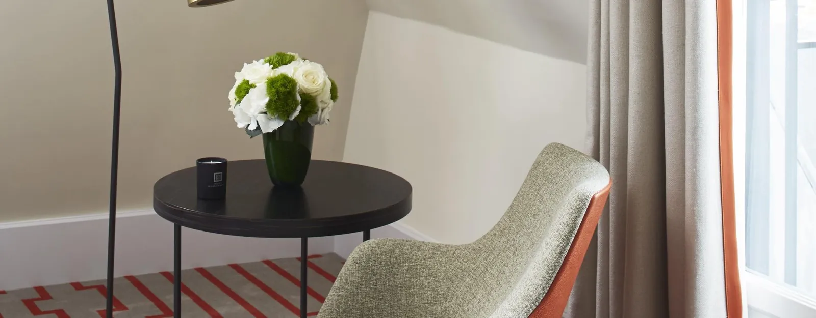 Chambre de l'Hôtel Montalembert Paris avec fauteuil sauge, table ronde et grande fenêtre, dans le 7e arrondissement
