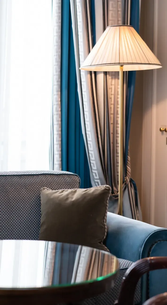 Blue velvet sofa and gold lamp beside a window in a room at Hôtel Napoléon, Paris