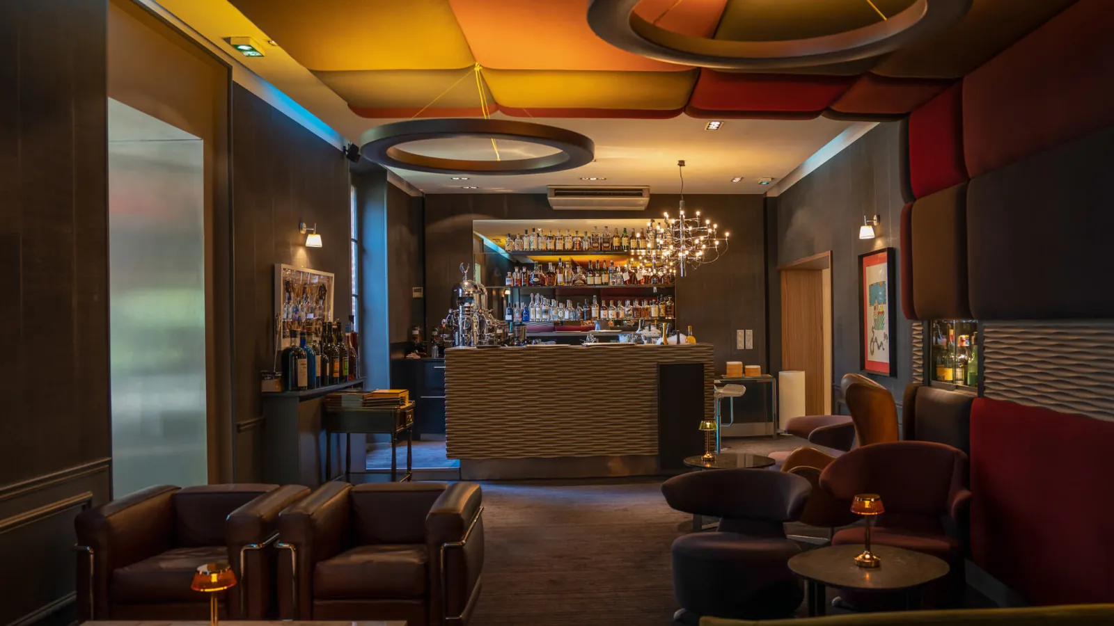 Lounge bar with leather armchairs and a backlit bottle wall at L'Assiette Champenoise, Reims
