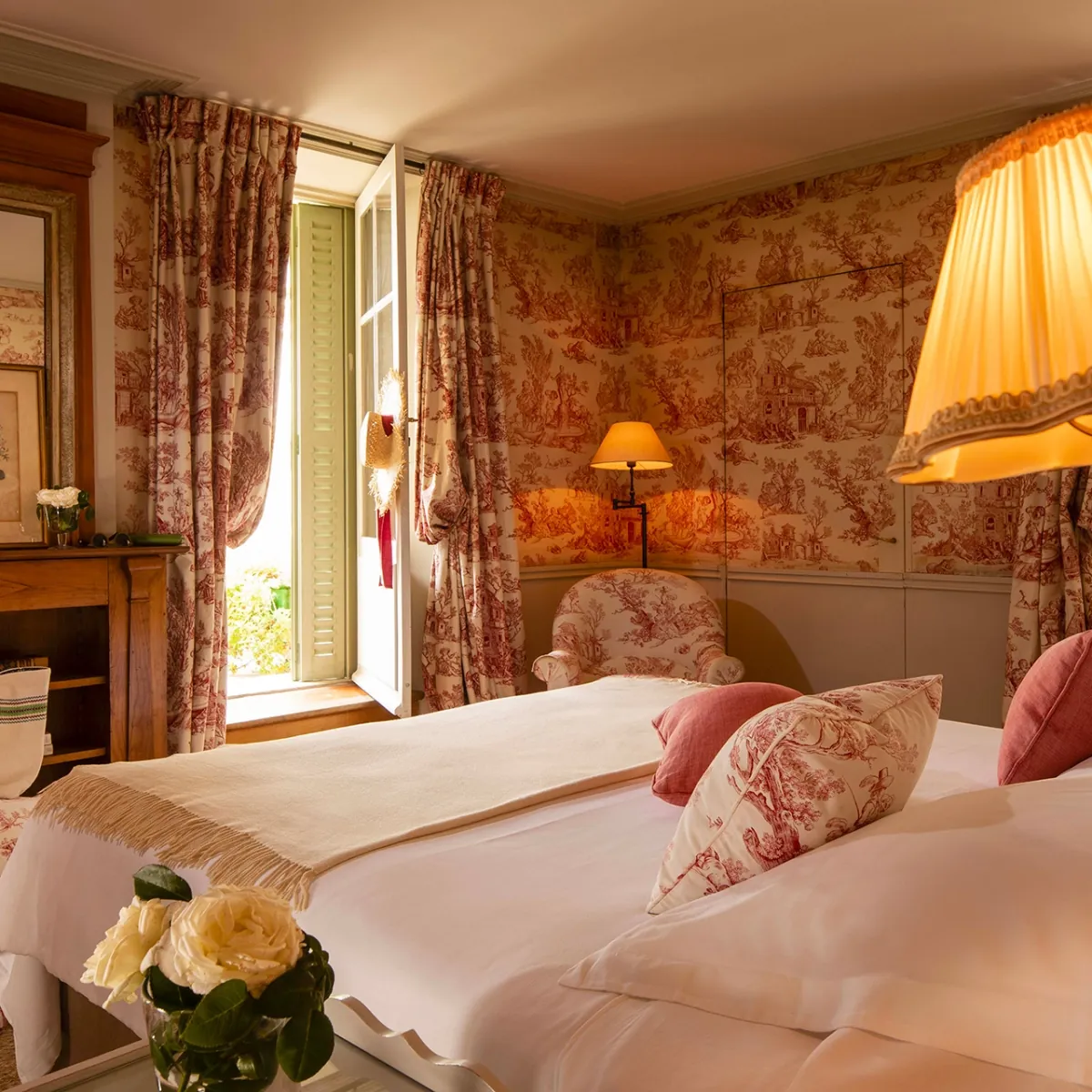 Guest room with toile de Jouy wallpaper, a dressed bed and a bedside lamp at La Mirande, Avignon