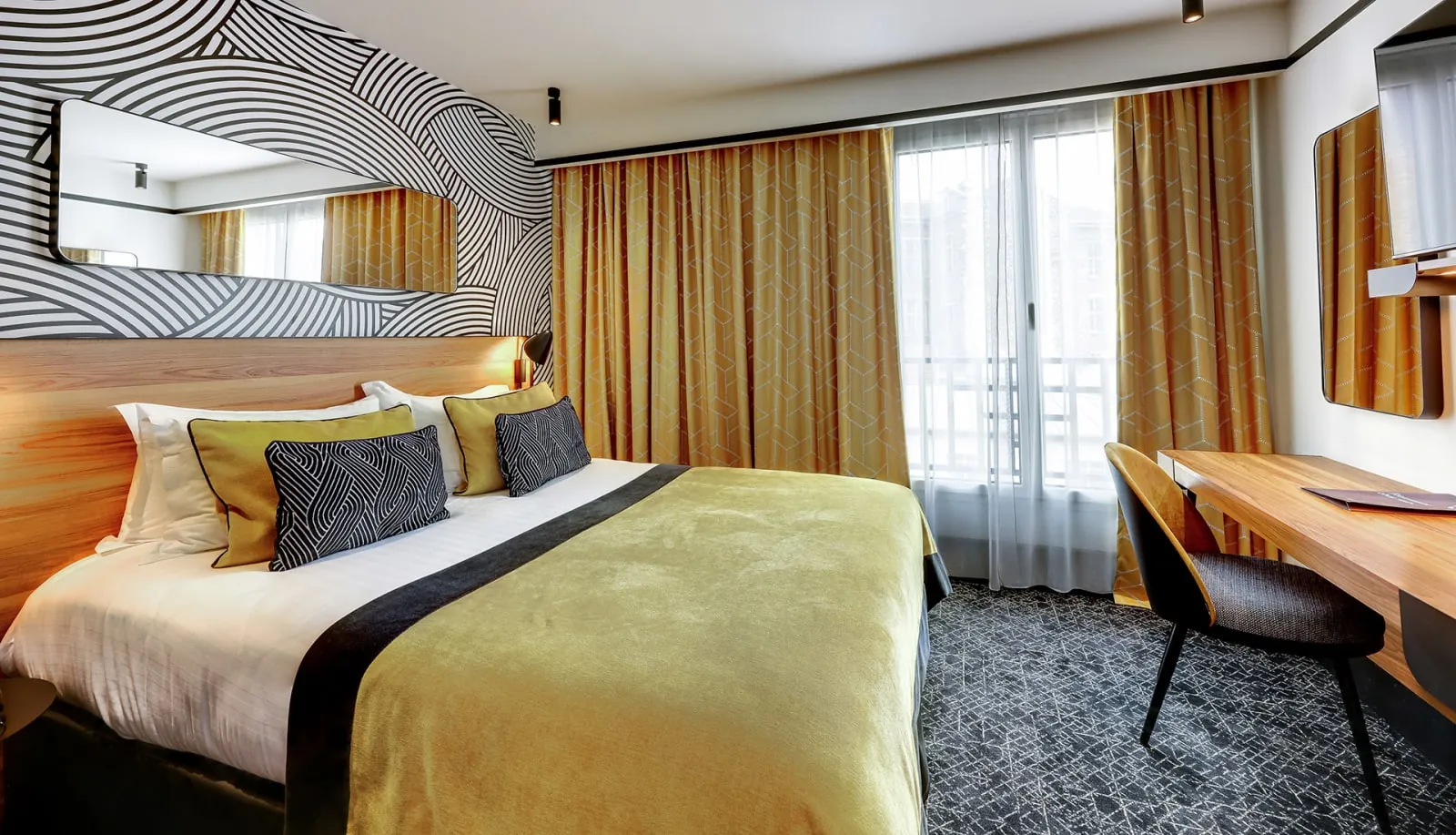 Double room with striped black-and-white wallpaper, yellow curtains and a wall-mounted television at La Villa Modigliani