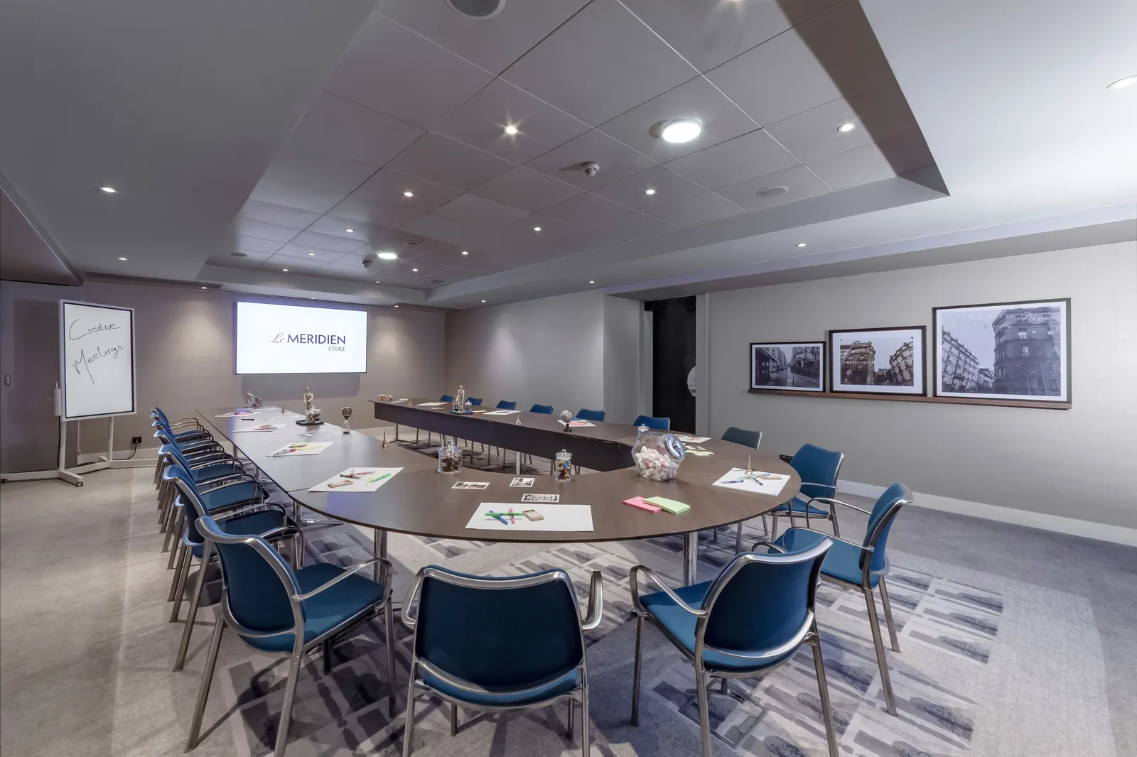 Meeting room set in a U-shape with blue chairs and a projection screen at Le Méridien Étoile, Paris