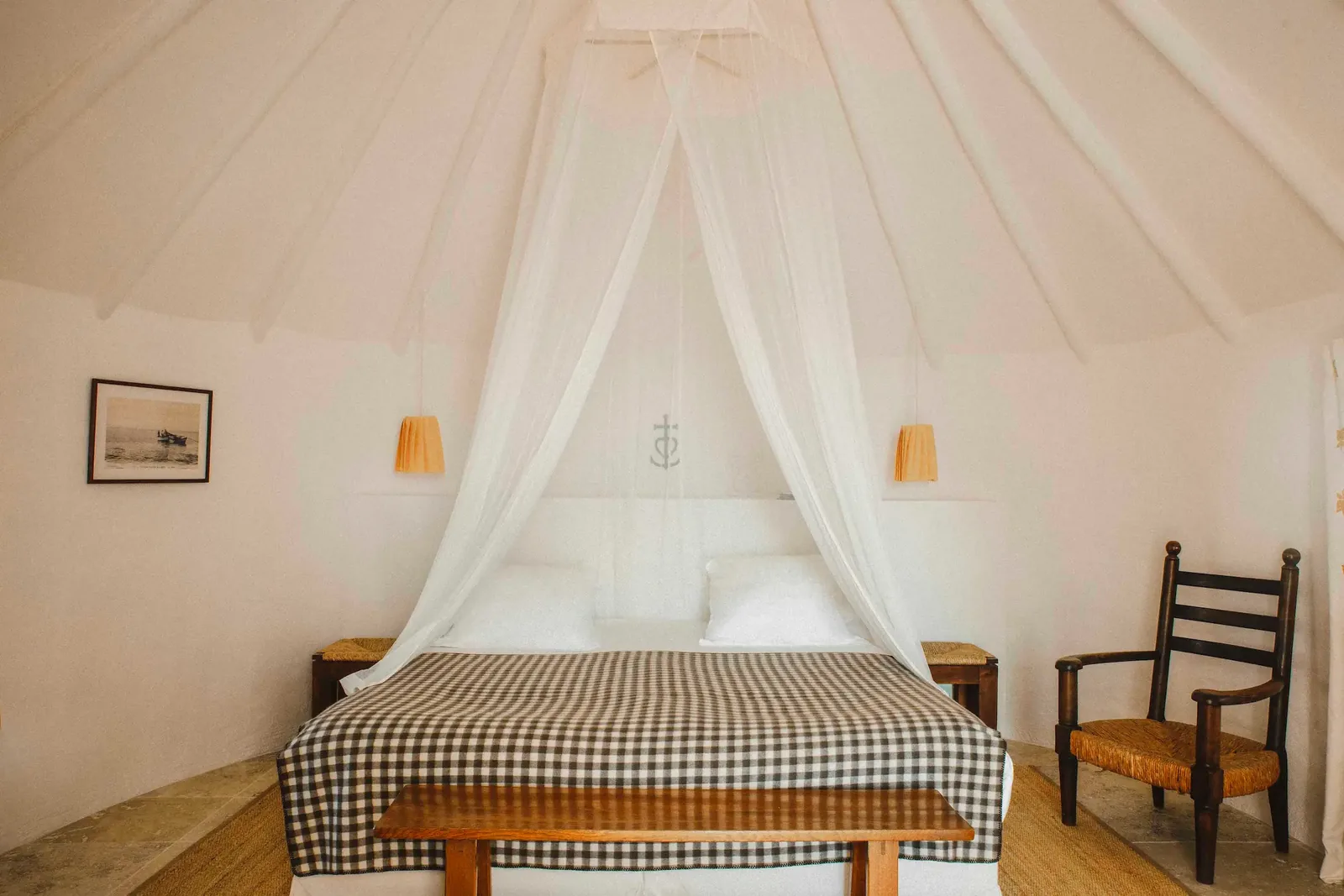 Double room with a canopy bed, checked bedspread and a wooden chair at Les Bains Gardians