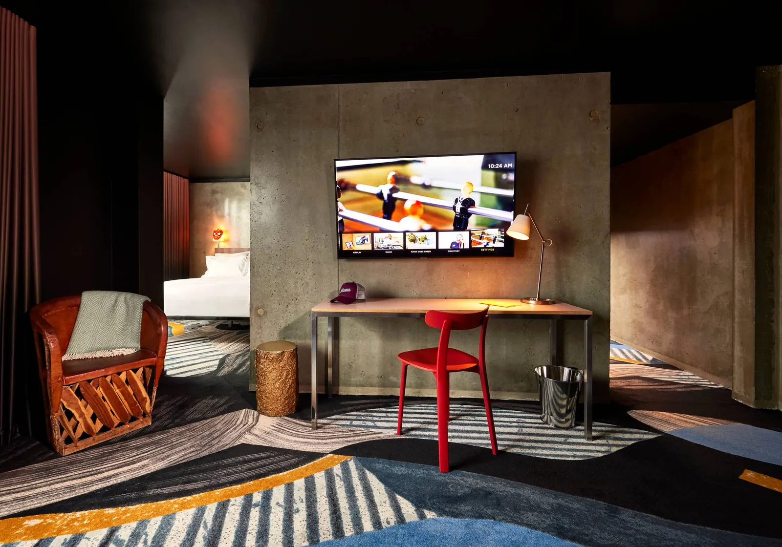 Guest room with a desk, red chair and wall-mounted TV at the Mama Shelter Paris East hotel