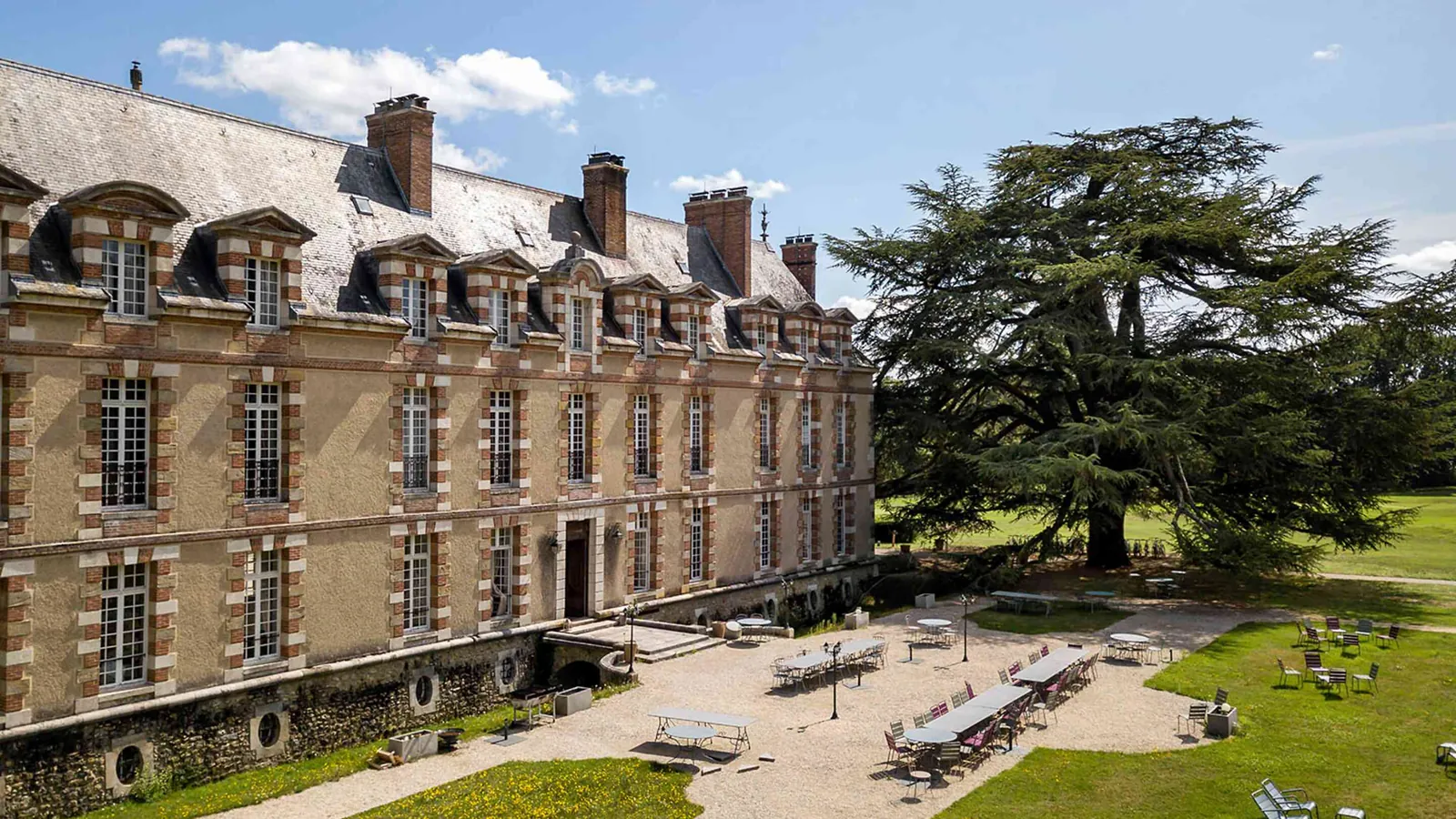 Façade de pierre du manoir, lucarnes et grand cèdre au Manoir des Prés Fleuris, dans les Yvelines