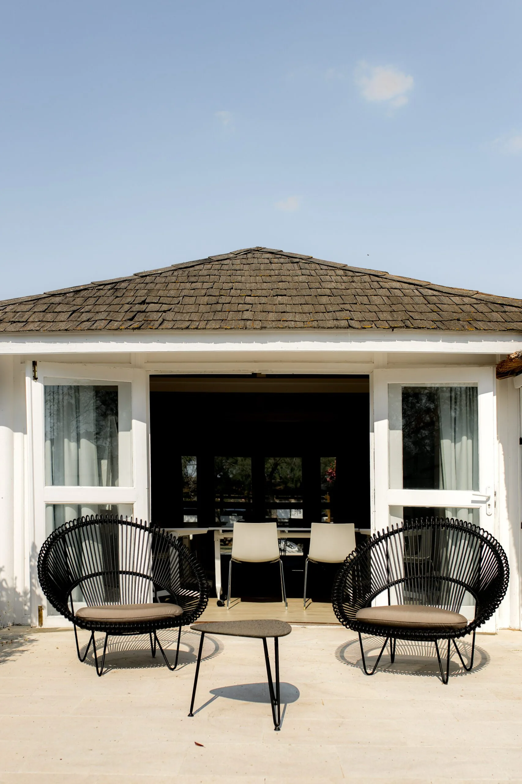 Covered outdoor lounge with black wicker chairs at Mas de la Fouque, Camargue