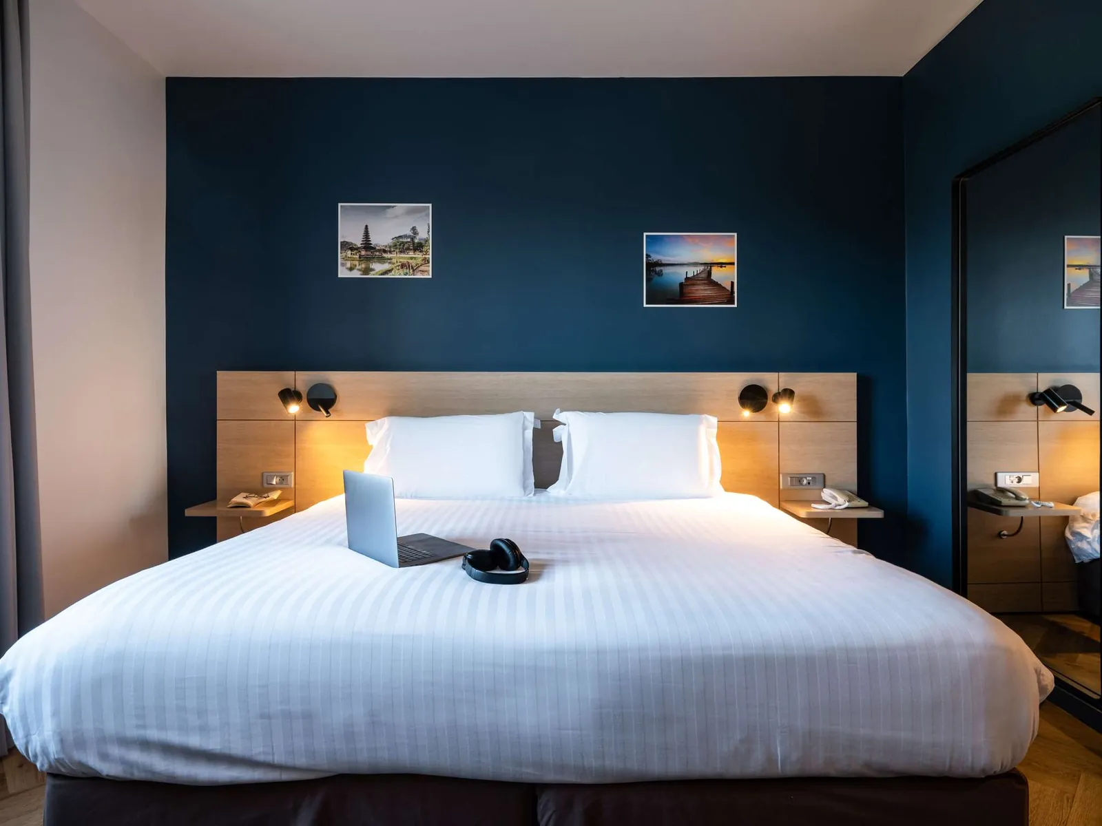 Chambre du Mercure Chantilly avec lit king size, mur bleu marine et appliques de lecture