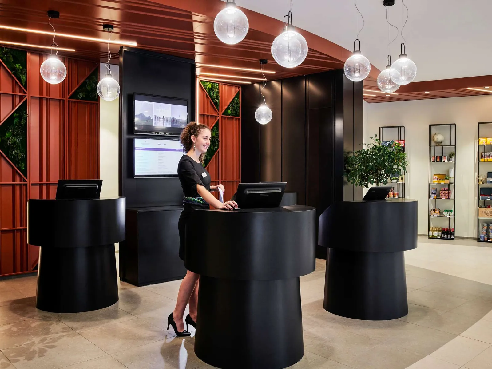 Reception desk in black and red tones with a pendant-lit lobby at Mercure Paris La Défense, Courbevoie