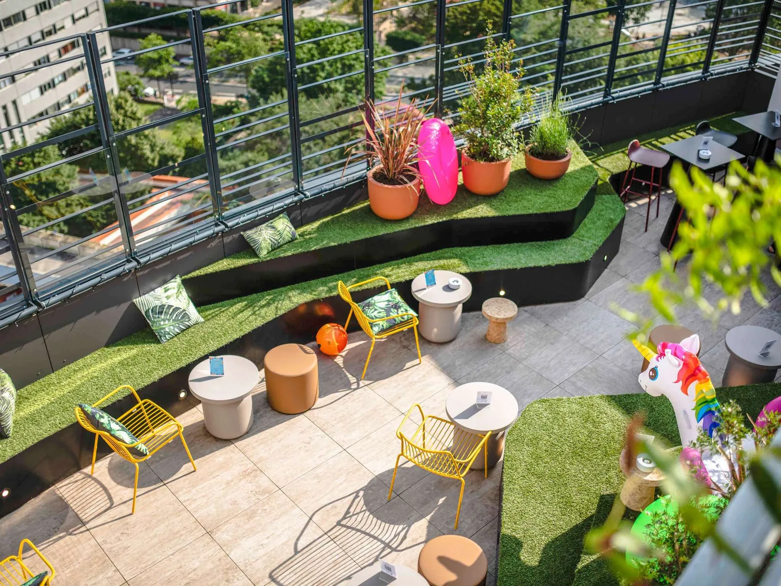 Rooftop terrace with artificial grass, planters and yellow lounge chairs at Mercure Paris La Défense