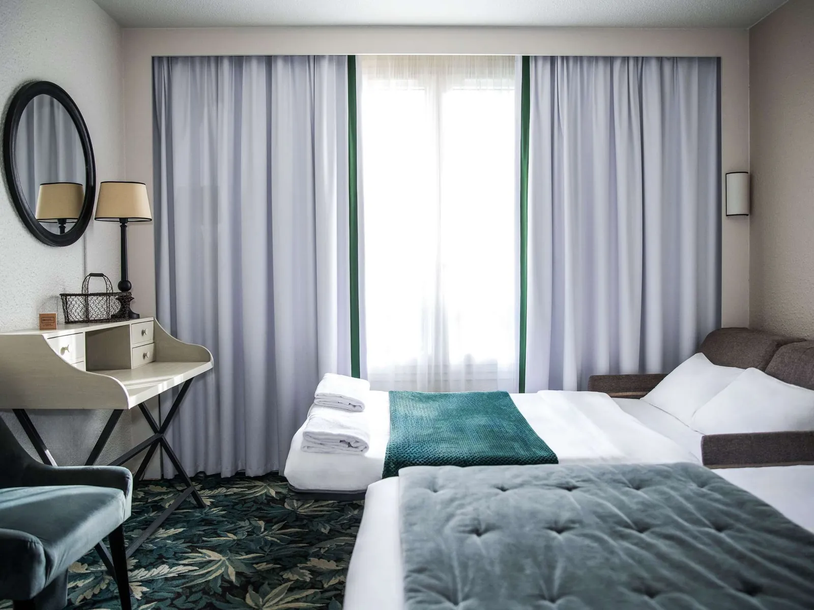 Chambre du Novotel Domaine de Maffliers avec lit double, plaid bleu canard et bureau