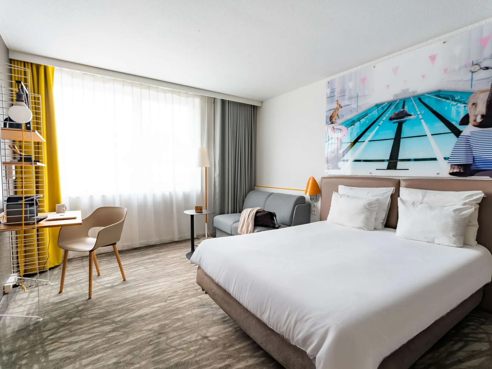 Double room with a pool print above the bed and yellow curtains at Novotel Évry-Courcouronnes