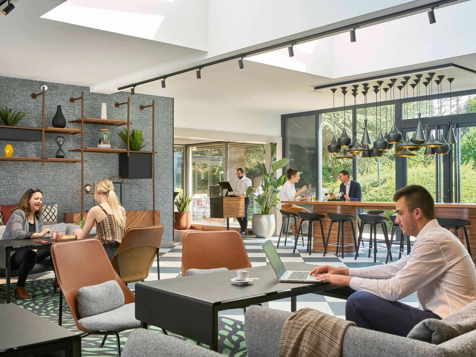 Lounge area with leather armchairs and guests working on laptops at Novotel Massy Palaiseau