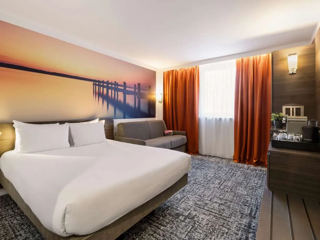 Bedroom with yellow cushions, green wall artwork and dark bedside tables at Novotel Paris Centre Bercy