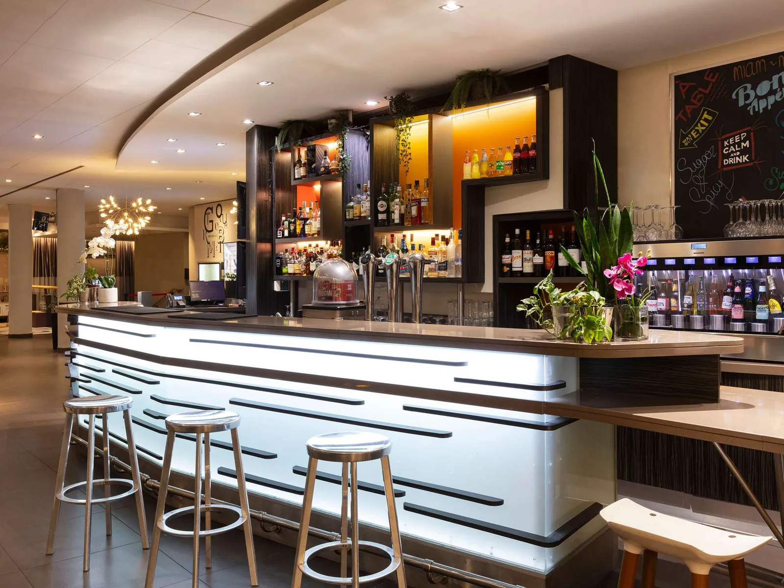 Bar counter with backlit shelves and high stools at Novotel Paris Saint-Denis Stade Basilique
