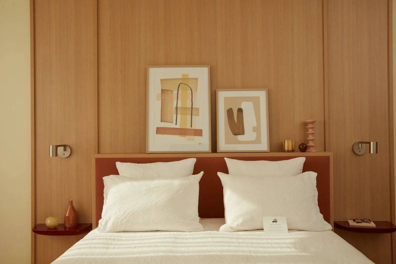 Chambre de l'OKKO Hotels Paris Rosa Parks avec mur en bois chaud, tête de lit terracotta et tableaux abstraits