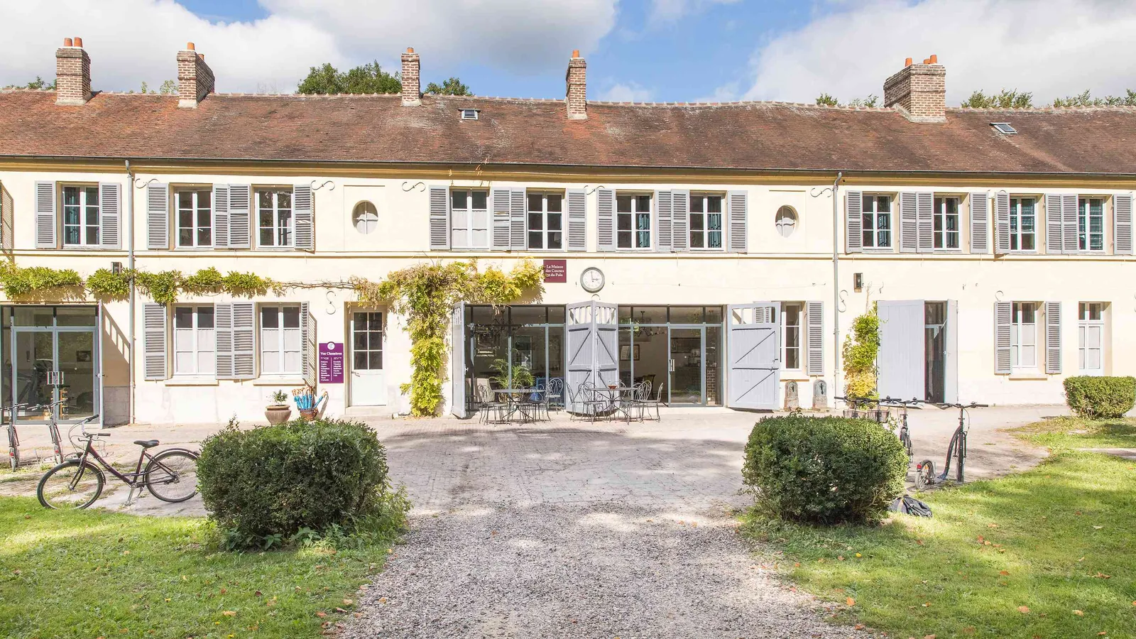 Converted barn-style building with a gravel courtyard and bicycles at Palais des Bords d'Oise, Val-d'Oise