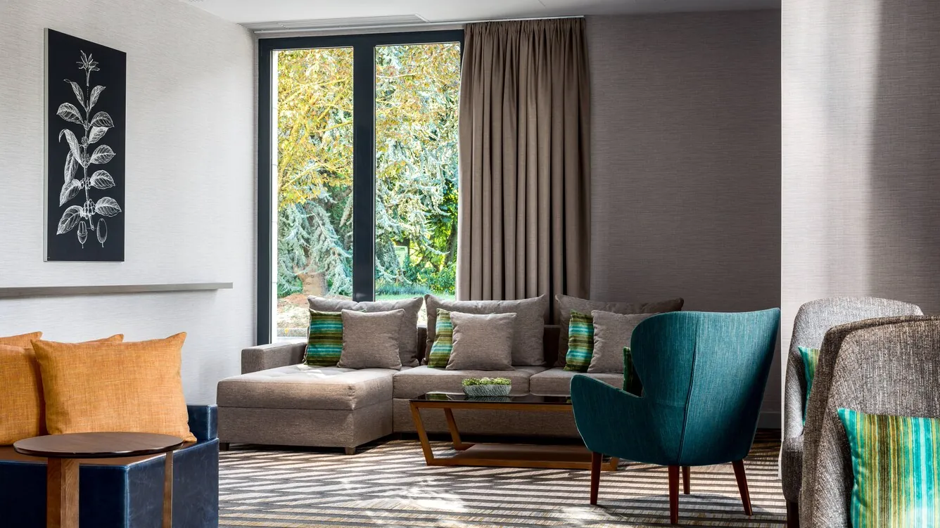 Espace détente de l'hôtel Paris Marriott Charles de Gaulle Airport avec fauteuils verts et canapé