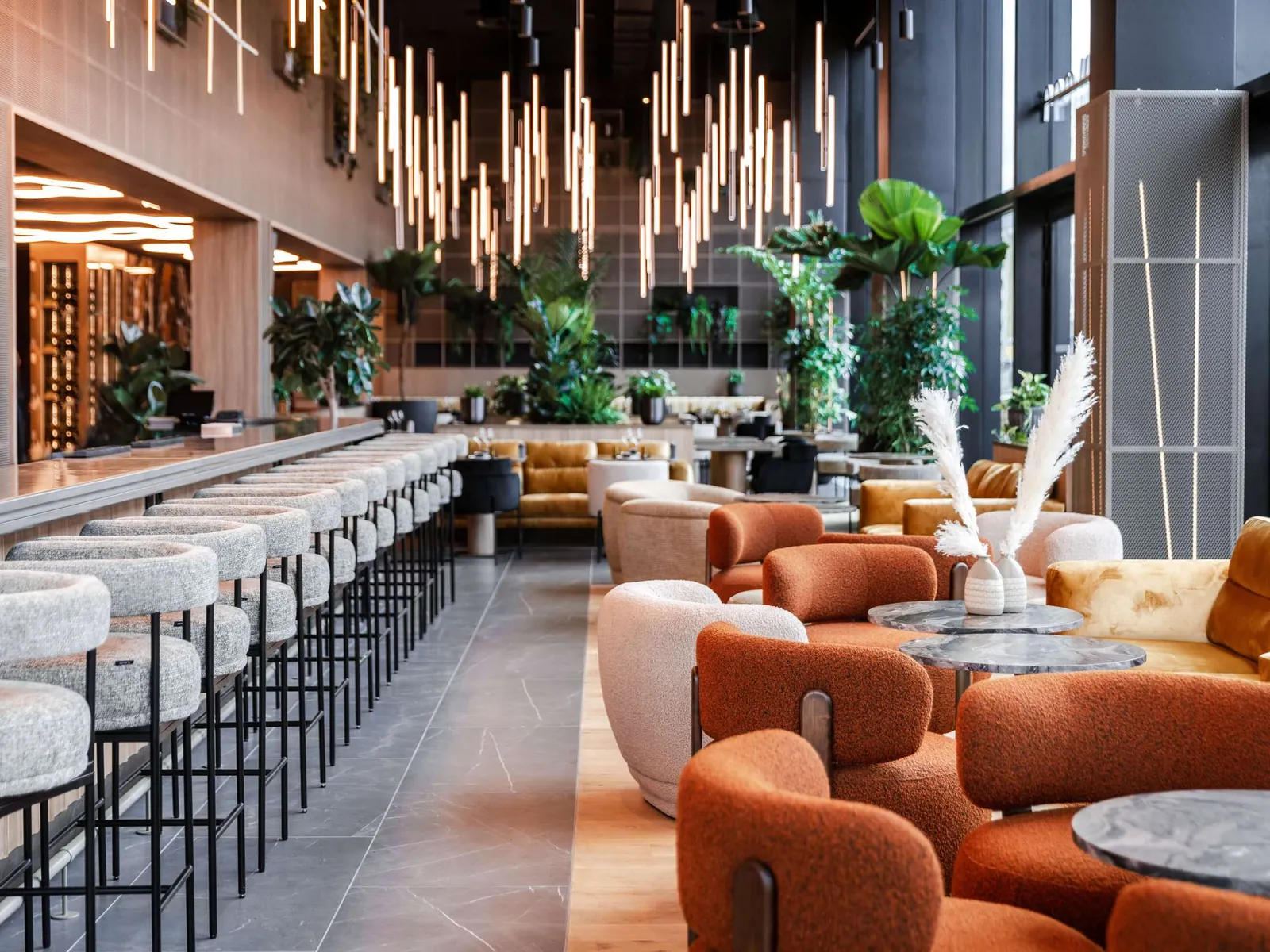 Lounge bar with orange armchairs and hanging lights at Pullman Lyon, Part-Dieu, Lyon