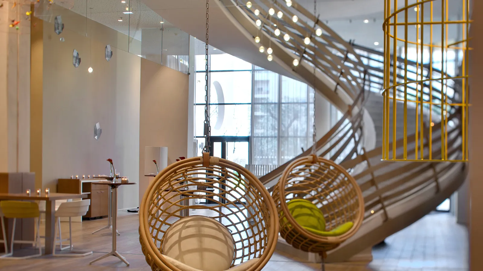 Lobby lounge with a sculptural staircase and wicker hanging chairs at Renaissance Aix-en-Provence Hotel
