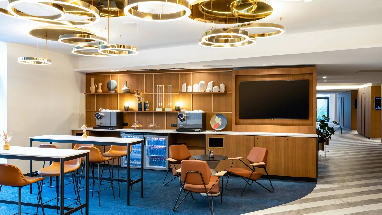 Lounge bar with bar stools, leather armchairs and pendant lights at Renaissance Bordeaux Hotel