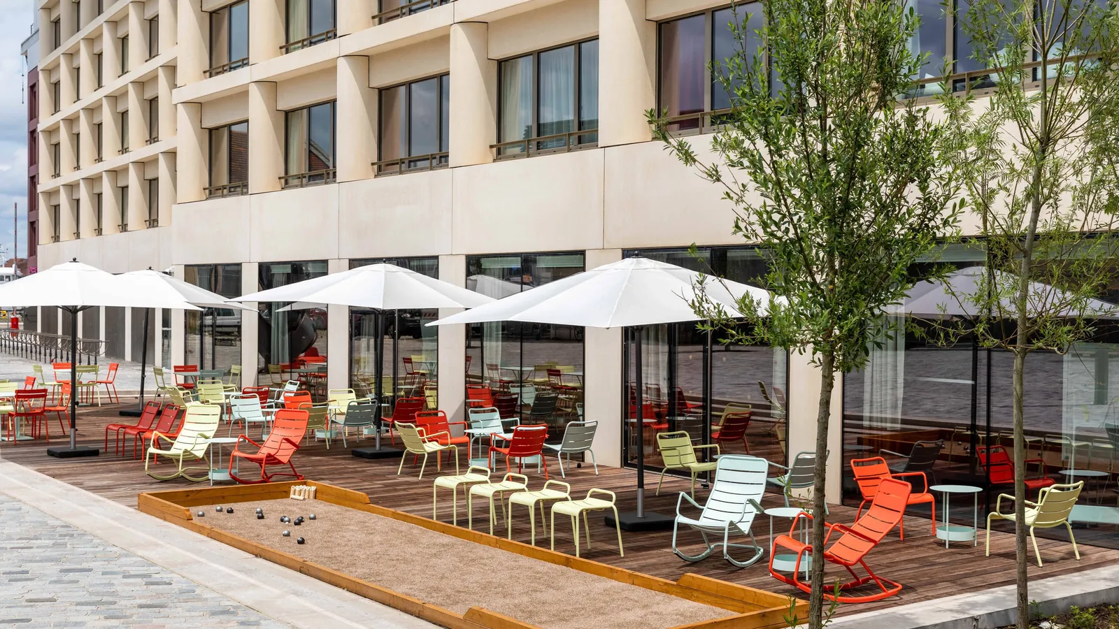 Outdoor terrace with red and white lounge chairs and parasols at Renaissance Bordeaux Hotel