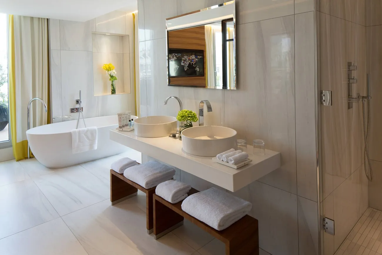 Bathroom with freestanding tub, twin basins and yellow flowers at Renaissance Paris République Hotel