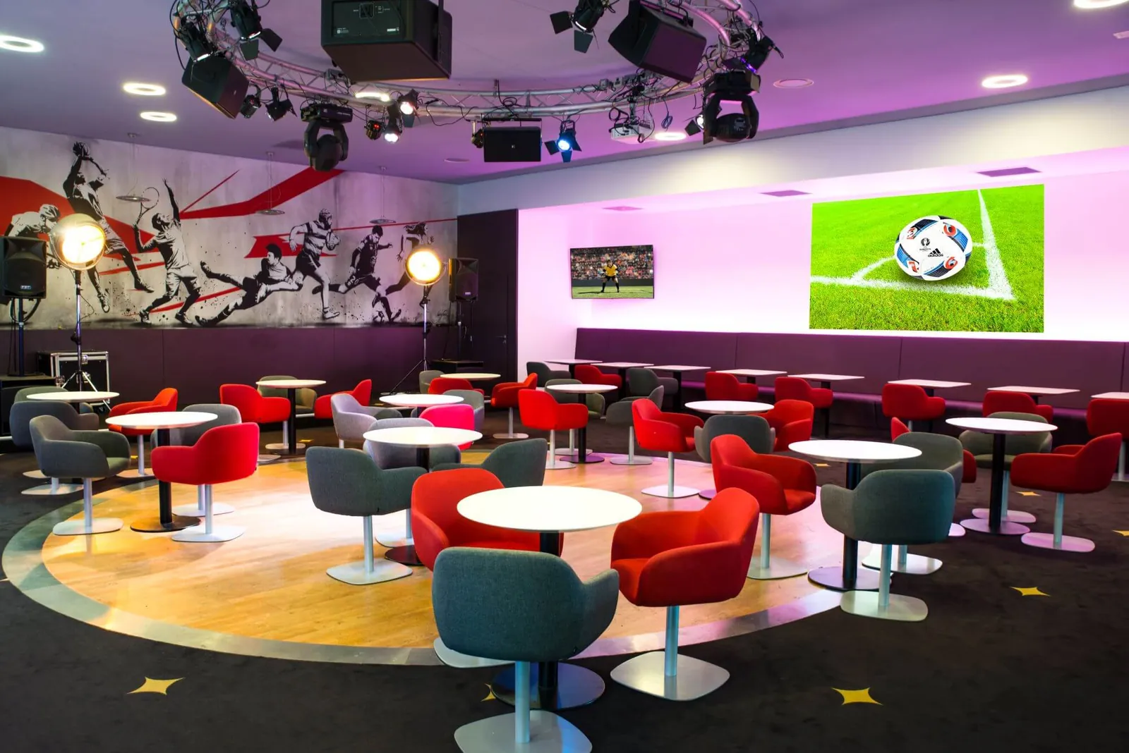 Salon du Café des Sports au Resort Barrière Ribeauvillé, avec fauteuils rouges et gris et fresque sportive