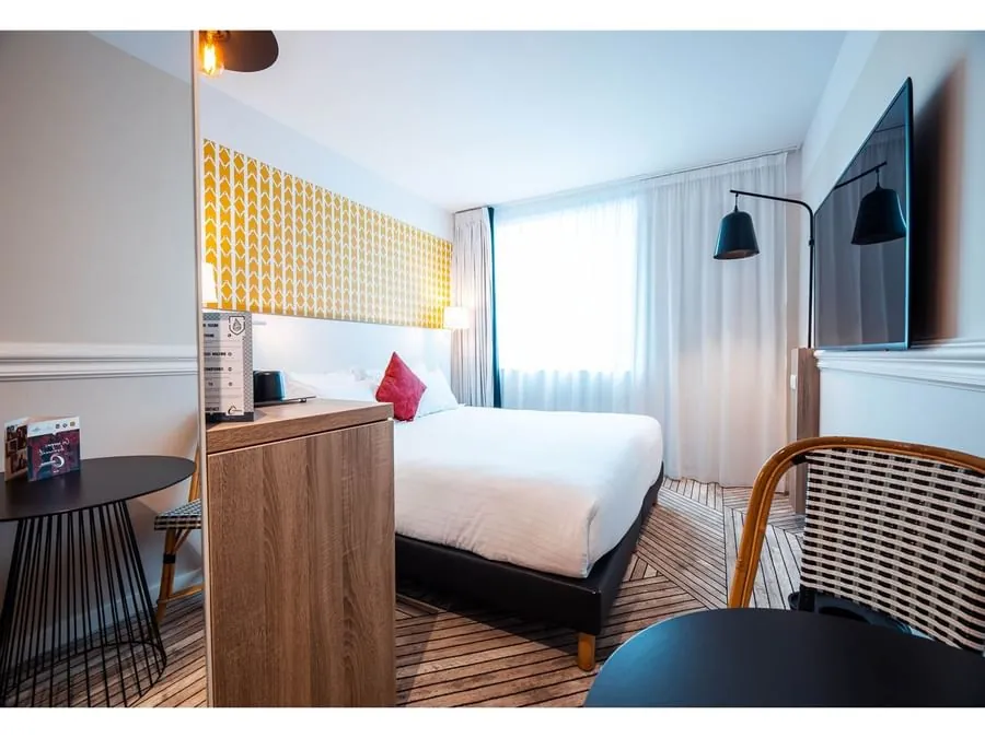 Chambre double de l'Hôtel Maison Montmartre avec panneau mural à motifs jaunes et bureau