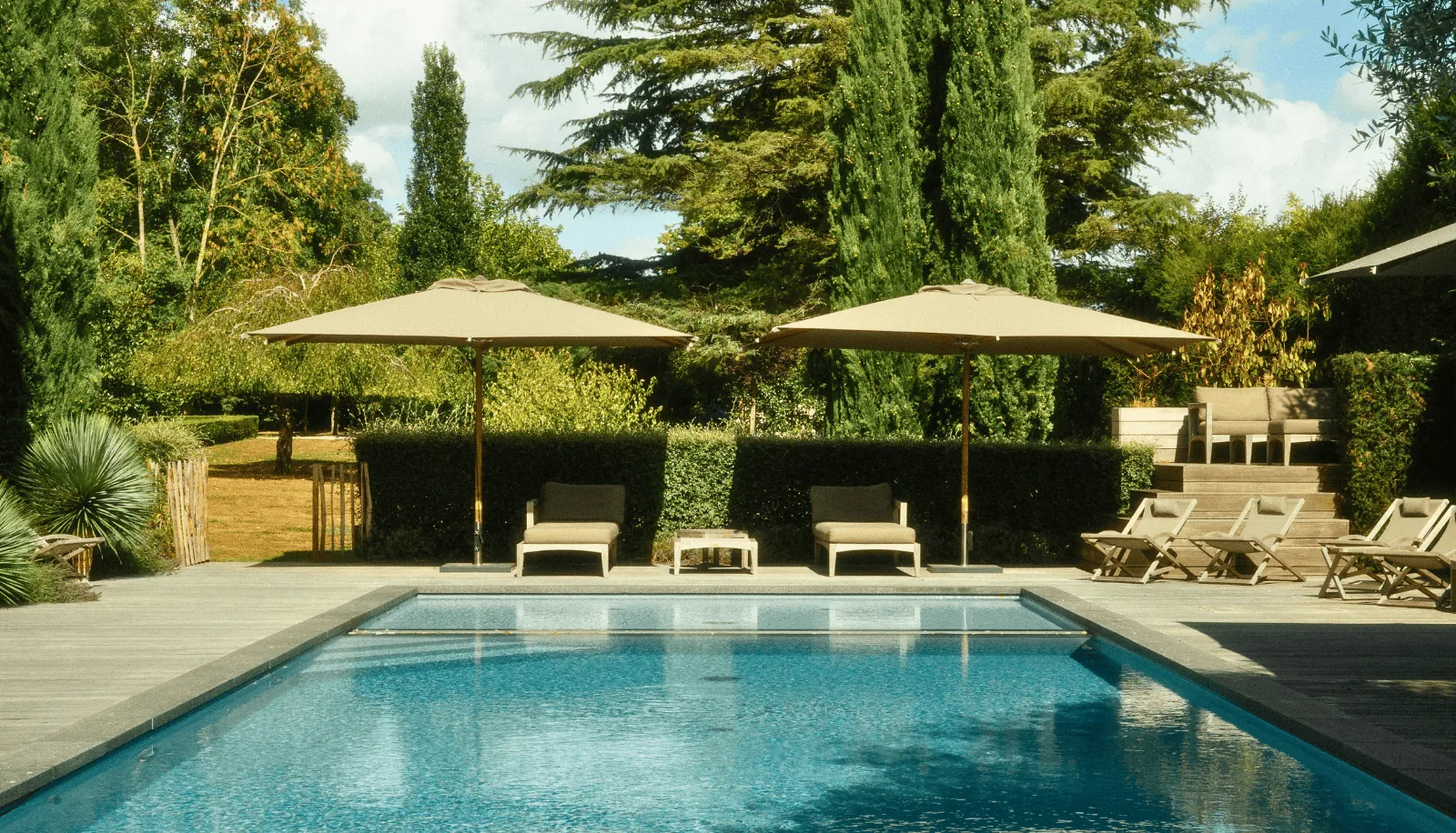 Piscine avec parasols et transats à Villa des Glycines, Île-de-France