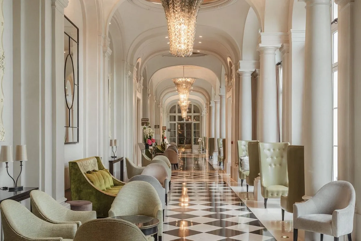 Galerie avec sol en marbre damier et fauteuils au Waldorf Astoria Versailles - Trianon Palace