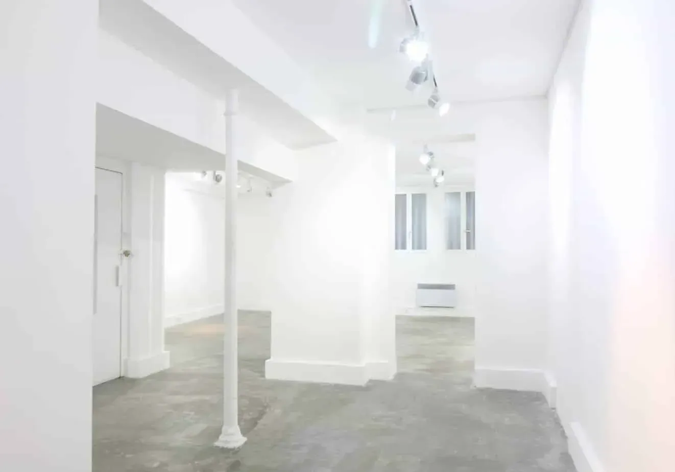 Corridor-style view of the white space with columns and wall lights