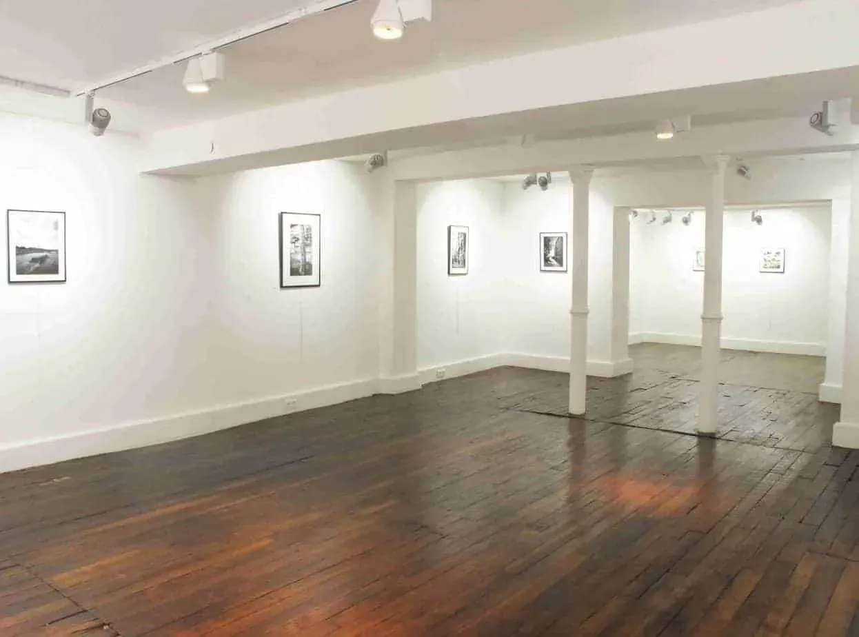 Room with framed prints on white walls and a wooden floor
