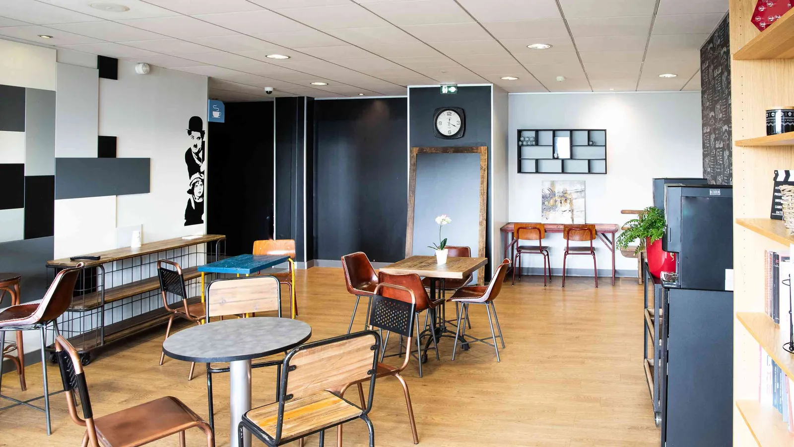 Espace de pause des Ateliers du Nord avec tabourets, tables rondes et mur graphique coloré