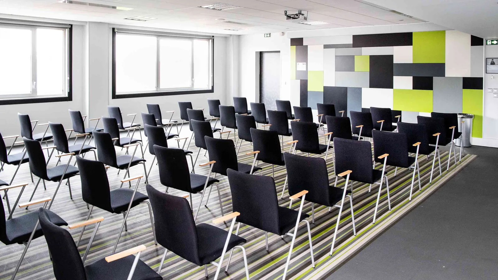 Salle de formation des Ateliers du Nord avec mur graphique et rangées de chaises noires