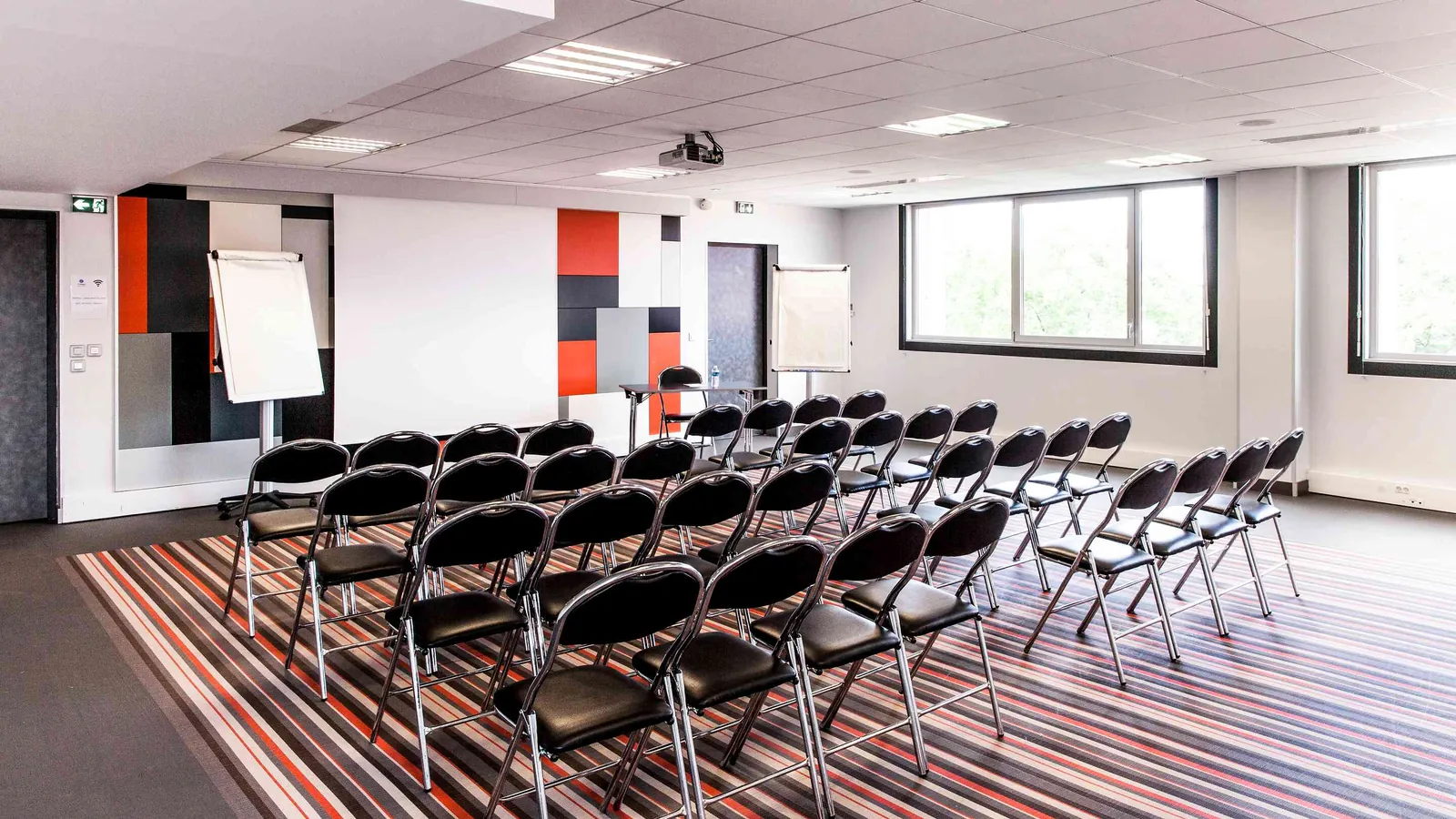 Salle de réunion des Ateliers du Nord avec écran de projection, chaises pliantes et moquette
