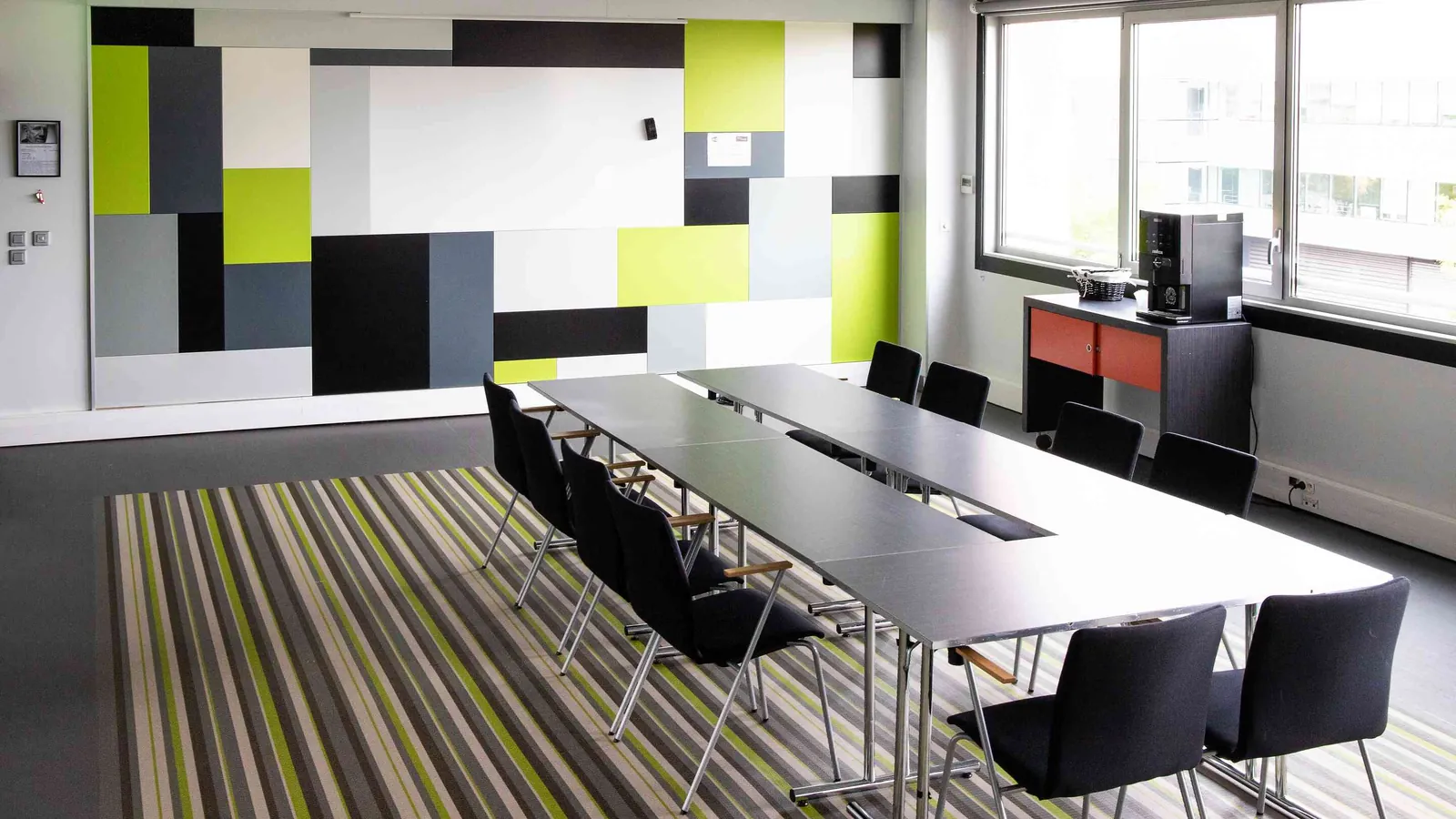 Salle des Ateliers du Nord en configuration conseil, grande table centrale et écran mural