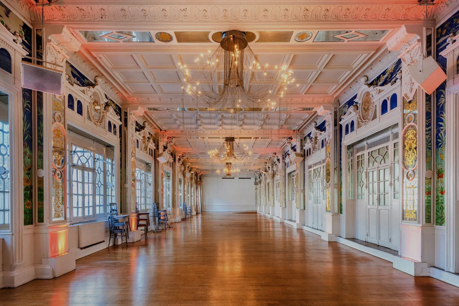 Long Belle Époque hall with mirrors, chandeliers and a parquet floor