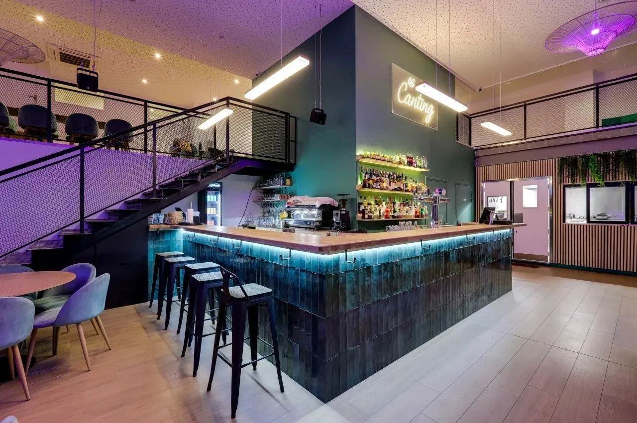 Bar counter with teal tiles, a mezzanine with metal railings and a neon sign reading Cangting.