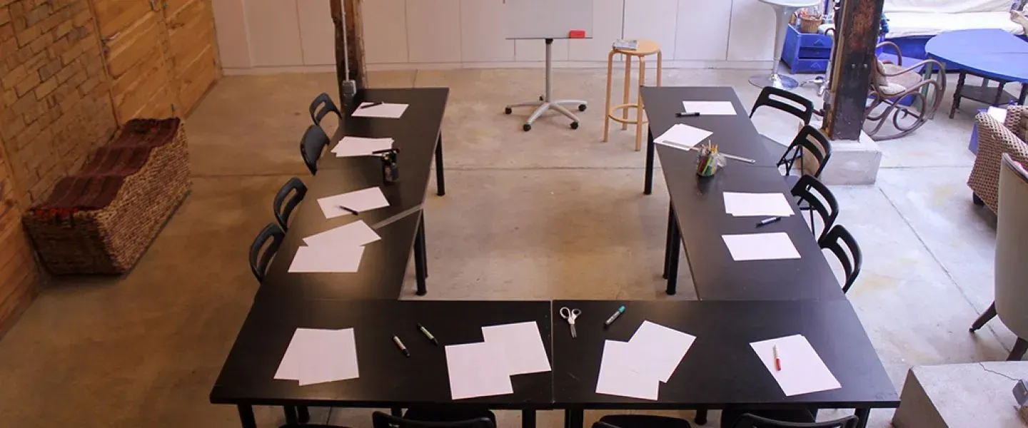 Workshop tables set in rows under a brick wall on a concrete floor