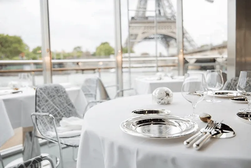 Electric boat deck with dressed dining tables and a view of the Eiffel Tower